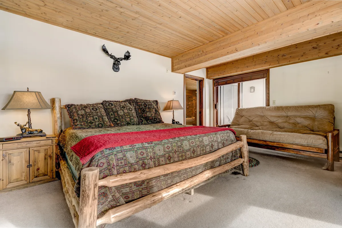 A warmly lit bedroom featuring a Queen or King bed with patterned bedding, complemented by wooden furniture and decorative wall art. The setting exudes comfort, privacy, and a sense of personal retreat, ideal for unwinding after a day of adventure.