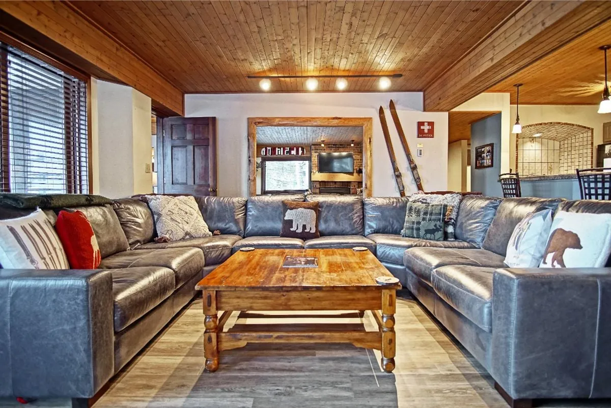 A spacious living area featuring a large sectional sofa with decorative pillows, a prominent wooden coffee table, and ample space for groups to gather. The inviting setup suggests comfortable socializing and relaxation, perfect for evenings in with friends or family.