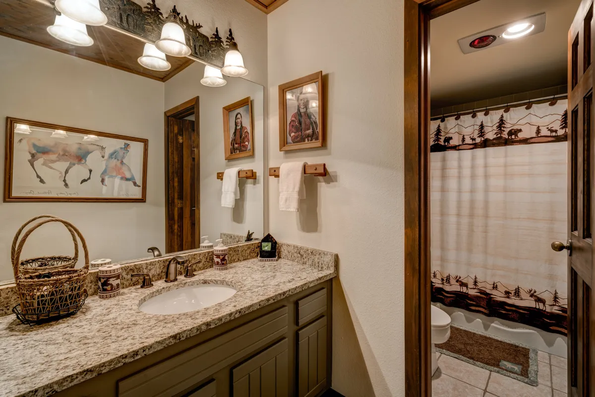 An inviting bathroom featuring a granite countertop, bright towels, framed artwork, and warm lighting. The space feels both functional and welcoming, perfect for morning routines or winding down after a busy day.